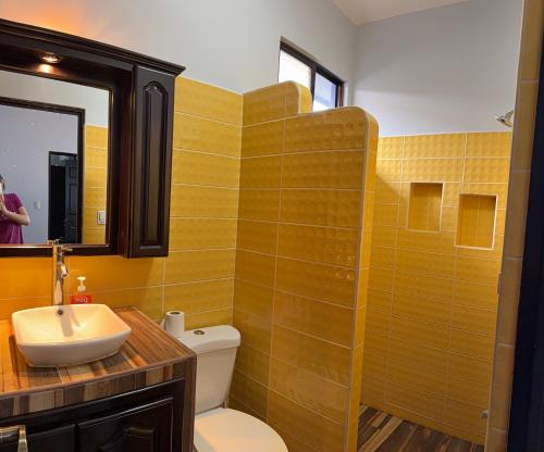 a bathroom with a sink and a toilet and a mirror at Casa Pacífico Esterillos in Esterillos