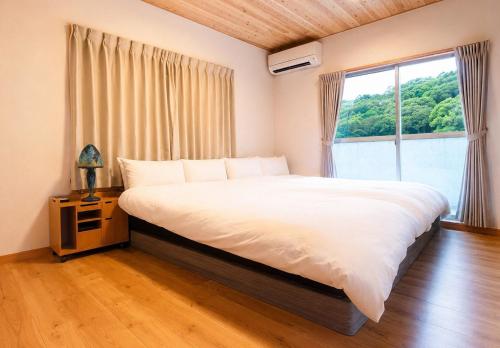 a bedroom with a large bed and a window at オリーブママのヤド 凪 バーベキュー機材レンタル可 in Shodoshima
