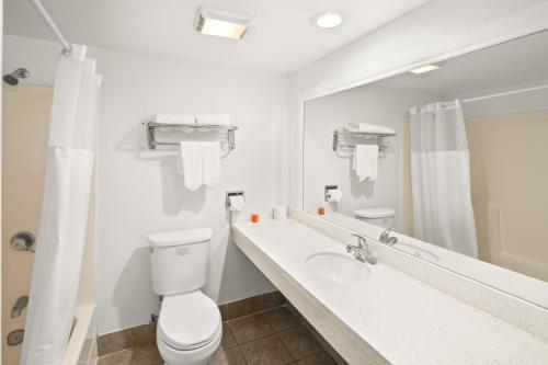 a bathroom with a toilet and a sink and a mirror at Vista Inn in Vista