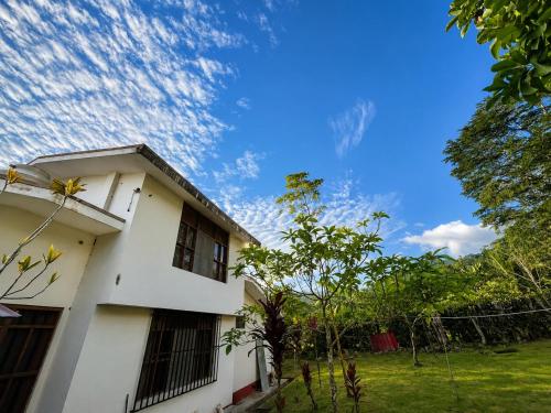 a white house against a blue sky with clouds at Refugio Amazónico in San Martín