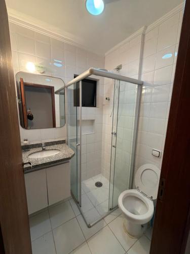 a bathroom with a toilet and a glass shower at Flat Beira Mar Caraguatatuba in Caraguatatuba