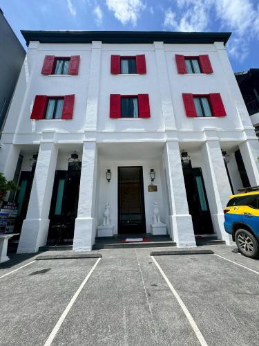a white building with red windows and a car in front at 99 The Gallery Hotel in Chiang Mai