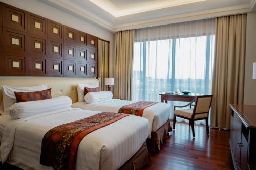 a hotel room with two beds and a desk at The Sunan Hotel Solo in Solo