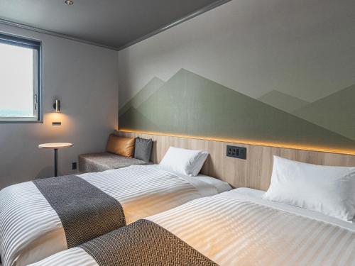 a hotel room with two beds and a chair at TsukubaNoYu Urban Hotel in Tsukuba