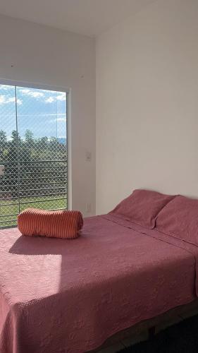 an orange pillow sitting on top of a bed with a window at Doce Lar 3 in Pouso Alegre