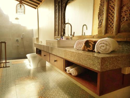a bathroom with a sink and a toilet at Joglo Villa with Private Pool in Pesanggaran