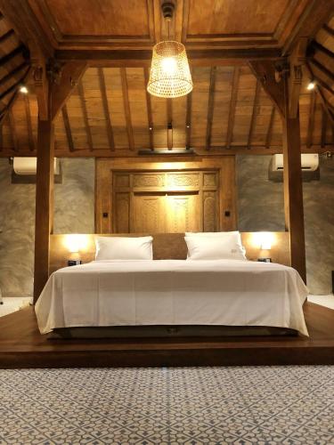 a bedroom with a large white bed with a chandelier at Joglo Villa with Private Pool in Pesanggaran