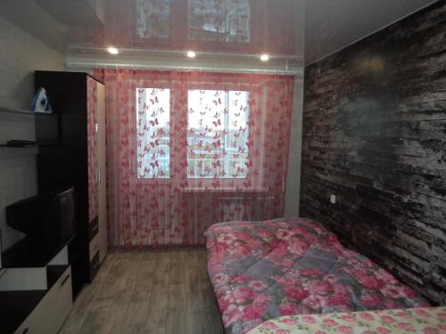 キーロフにあるApartments Azina 17のレンガの壁、窓、ベッド付きのベッドルーム1室が備わります。