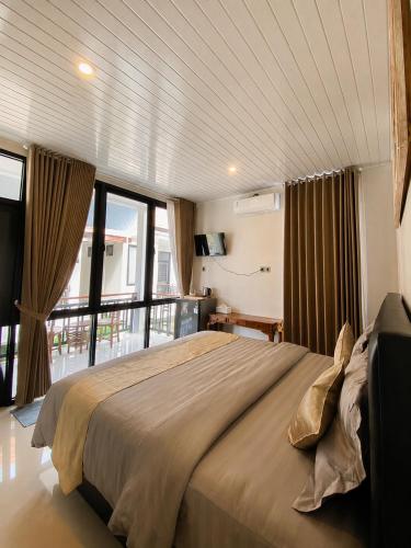 a bedroom with a large bed and a balcony at Pondok Biu 2 in Denpasar