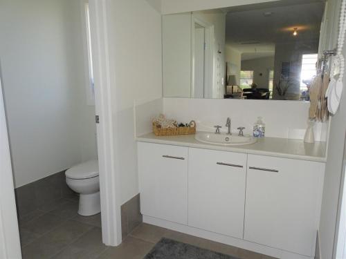 a white bathroom with a toilet and a sink at Ripplesea in Port Moonta