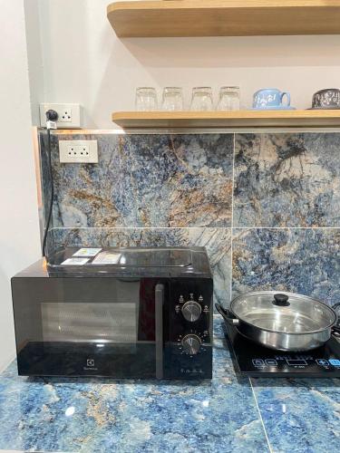 a kitchen with a toaster oven and a pan on a counter at Rose & Nainee House Hatyai in Ban Tha Thon