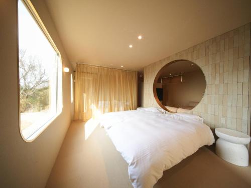 a bedroom with a bed with a mirror and a window at Over the MOON in Awaji