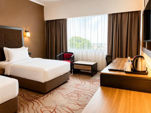 a hotel room with two beds and a desk at Impiana Hotel Ipoh in Ipoh
