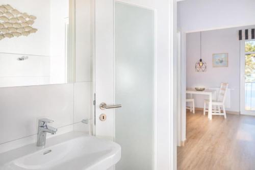 a white bathroom with a sink and a table at Ille in Wittdün