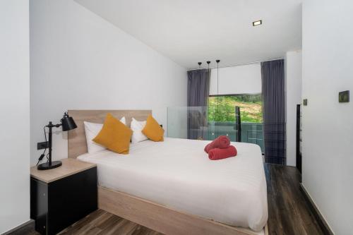 a bedroom with a white bed with two red stuffed animals on it at Duplex Loft 5 Pools and Gym near Nai Harn Beach- UTL B119 in Rawai Beach