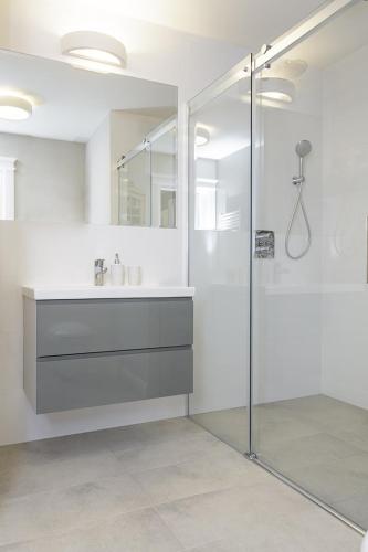 a white bathroom with a sink and a shower at Arra Suites kempegowda Airport Hotel in Devanhalli