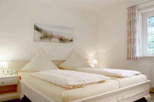 two beds in a bedroom with white walls at Eismoewe in Nebel