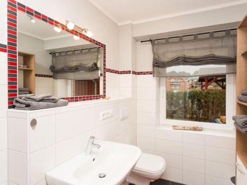 a white bathroom with a sink and a mirror at kleiner-Fiete in Wittdün