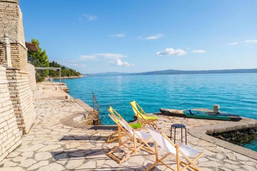 a group of lawn chairs sitting next to the water at Seafront Escape - 4BR Beachfront Villa for 8 in Šibuljina