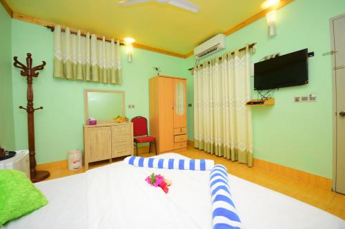 a bedroom with a bed and a tv on the wall at Olhumathi View Inn in Ukulhas