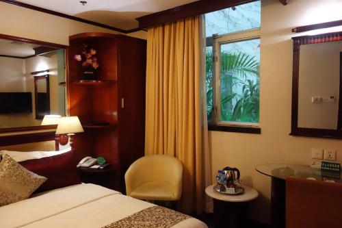 um quarto de hotel com uma cama e uma cadeira e uma janela em Macau Masters Hotel em Macau