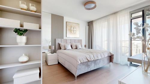a white bedroom with a bed and a window at Eurovea Tower Apartments free Parking in Bratislava