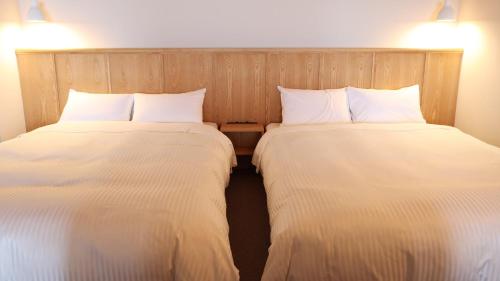 two beds sitting next to each other in a room at ジローズガーデン in Ishinomaki