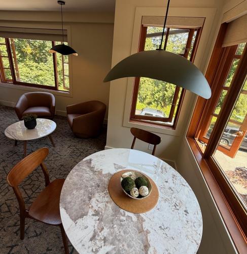 a room with a table and chairs and windows at Artisan Suites on Bowen in Bowen Island