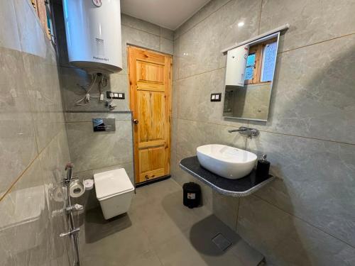 a bathroom with a sink and a toilet and a mirror at French Woods Cottages in Srinagar