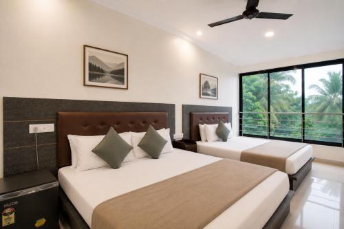 two beds in a room with two windows at MogPrach Boutique in Calangute