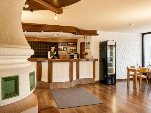 a man standing at a kitchen counter with a refrigerator at Sunday Hotel Willingen in Willingen