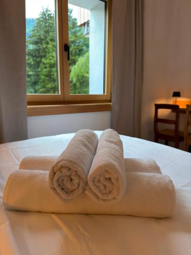two towels sitting on top of a bed with a window at Chalet du Lac in Charmey