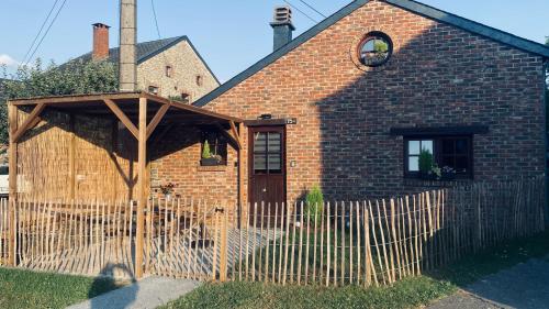 a brick house with a fence in front of it at L Abri douillet in Libin