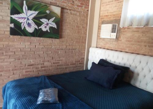 a bedroom with a blue bed with a painting on the wall at Recanto Barretos in Barretos