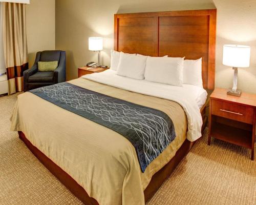 a hotel room with a large bed and a chair at Comfort Inn Conference Center Pittsburgh Penn Hills in Churchill