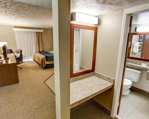 a hotel room with a bathroom with a bed and a mirror at Comfort Inn Conference Center Pittsburgh Penn Hills in Churchill