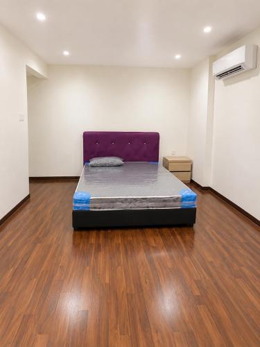 a bed in a room with a wooden floor at Anjung Seri Residence in Masai