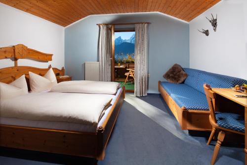 sypialnia z łóżkiem, kanapą i oknem w obiekcie Pension Lugeck w mieście Berchtesgaden