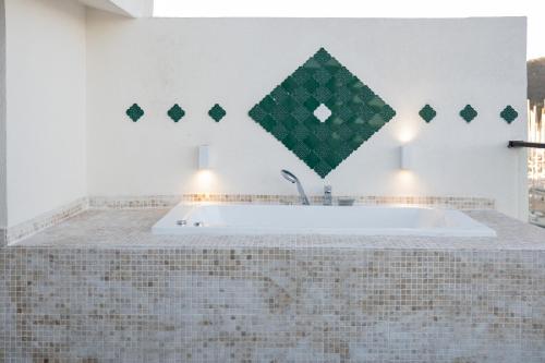 a bath tub in a bathroom with a tiled wall at Harbour Suites Fethiye in Fethiye