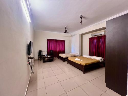 a room with two beds and a tv in it at Manipal Downtown in Manipal