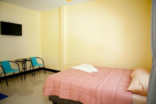 a bedroom with a bed and a table and chairs at Bannrommai Sattahip in Sattahip
