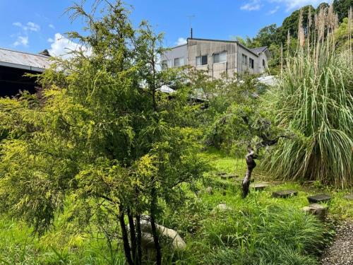 Eine Wiese mit Bäumen und ein Gebäude im Hintergrund in der Unterkunft Fukuroutei in Sosa