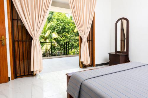 a bedroom with a bed and a balcony at Ivy Garden Retreat in Gampola
