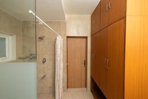 a bathroom with a shower with a wooden door at Ishan Apartments 3BHK in Vadodara
