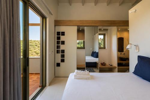 a bedroom with a large white bed with a large window at Physis Villas Chania in Ayiá