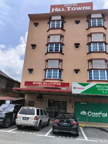 two cars parked in a parking lot in front of a building at Hotel O Hilltowne in Kampong Kawak
