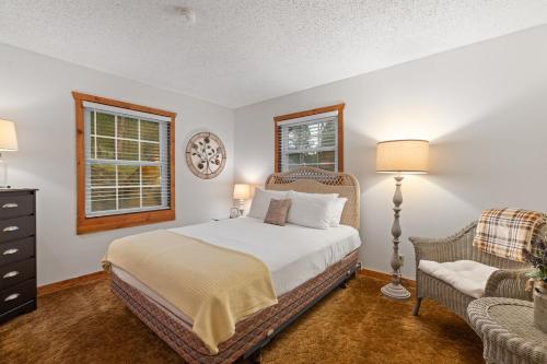 a bedroom with a bed and a chair and two windows at Stones Throw in Hill City