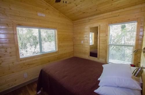 DescansoにあるOakzanita Springs Camping Resort Cottage 4の木造キャビン内のベッド1台が備わるベッドルーム1室を利用します。