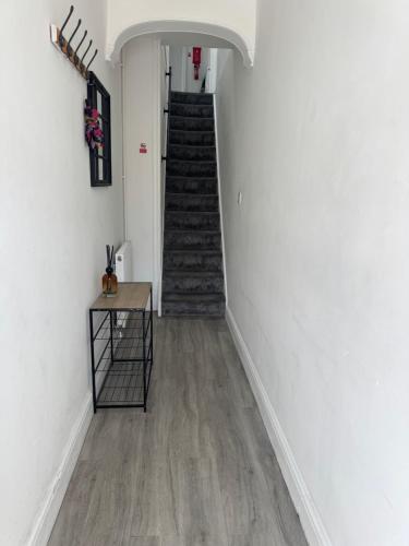 a hallway with a staircase with white walls and wooden floors at 31a locking road in Weston-super-Mare