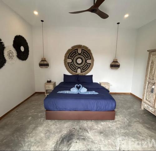 a bedroom with a blue bed with a fan at Villa jay in Na Mueang